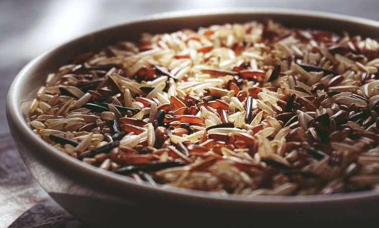 Macro shot of a ceramic bowl filled with colorful mixed wild rice, highlighting textures.