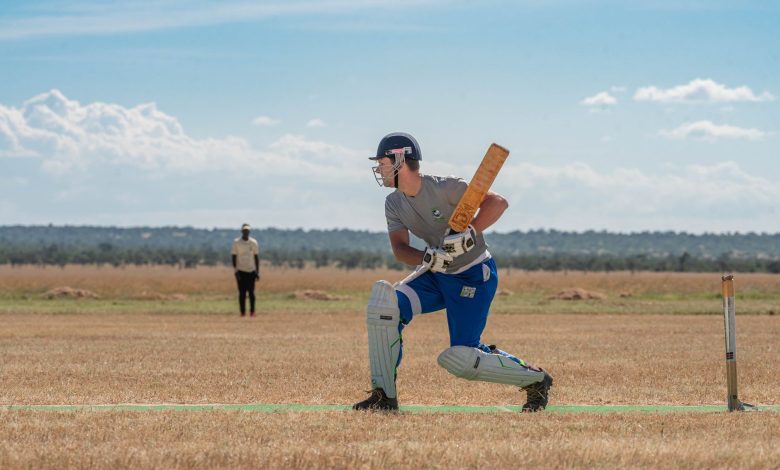 Cricketer prepares to bat on a bright sunny day in the field, displaying focus and concentration.