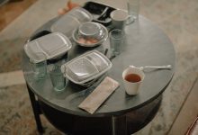 A cozy home setting with a table covered in takeaway food containers and used dishes.