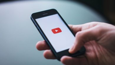 Close-up of a hand holding a smartphone displaying the YouTube app on the screen.