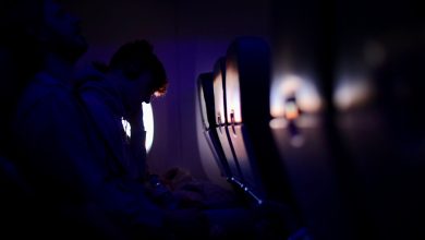Passengers resting in a dimly lit airplane with purple ambient lighting, showcasing a peaceful travel experience.