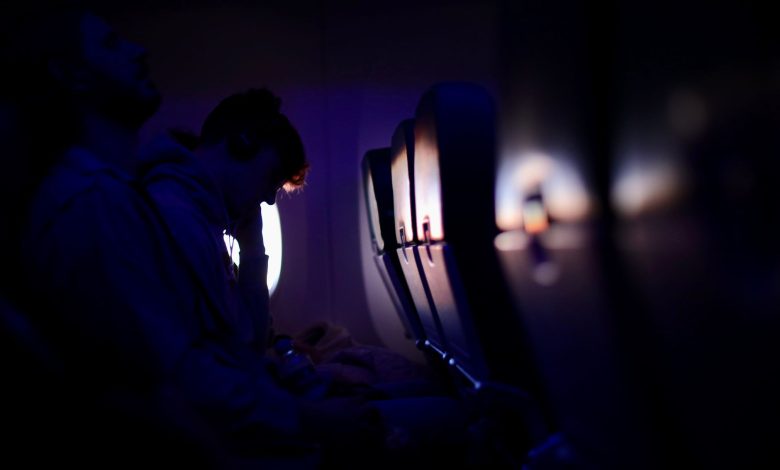Passengers resting in a dimly lit airplane with purple ambient lighting, showcasing a peaceful travel experience.