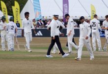 Cricket players and umpire on field during a match in Cheltenham, England.