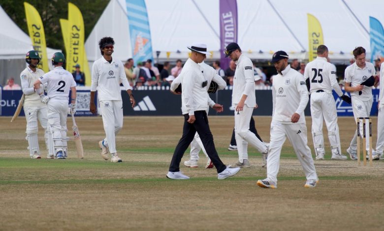 Cricket players and umpire on field during a match in Cheltenham, England.