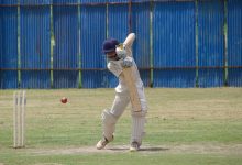 Cricket player in action, batting on a grass field in Gahunje, India.