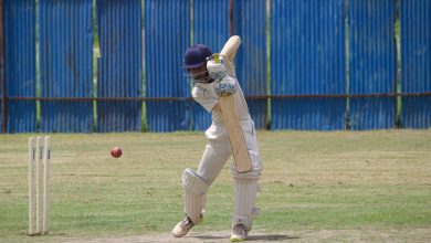 Cricket player in action, batting on a grass field in Gahunje, India.