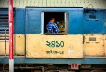 A conductor operating a train, focusing on control panel inside the locomotive cabin.