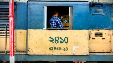A conductor operating a train, focusing on control panel inside the locomotive cabin.