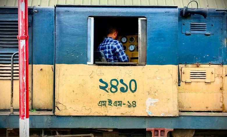 A conductor operating a train, focusing on control panel inside the locomotive cabin.