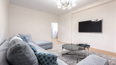 Contemporary room interior with couch and TV with black screen against tables under shiny chandelier in house