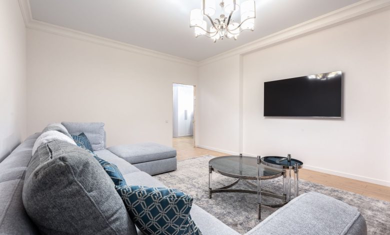 Contemporary room interior with couch and TV with black screen against tables under shiny chandelier in house