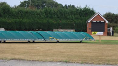 Cricket pitch covers at a sports field in Audley, England, on a clear day.