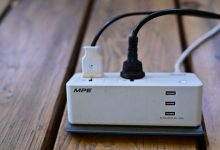 A power strip with multiple USB ports and cables connected on wooden surface.