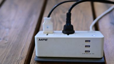 A power strip with multiple USB ports and cables connected on wooden surface.