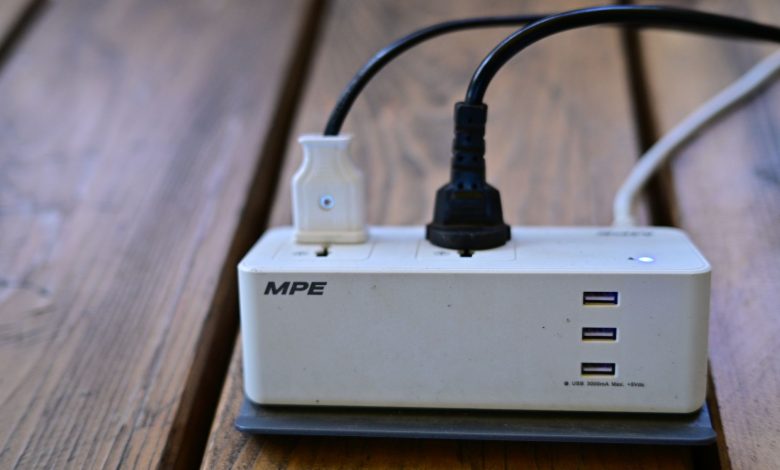 A power strip with multiple USB ports and cables connected on wooden surface.