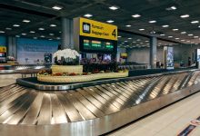 Modern baggage claim area at Suvarnabhumi Airport in Bangkok with luggage carousel and signage.
