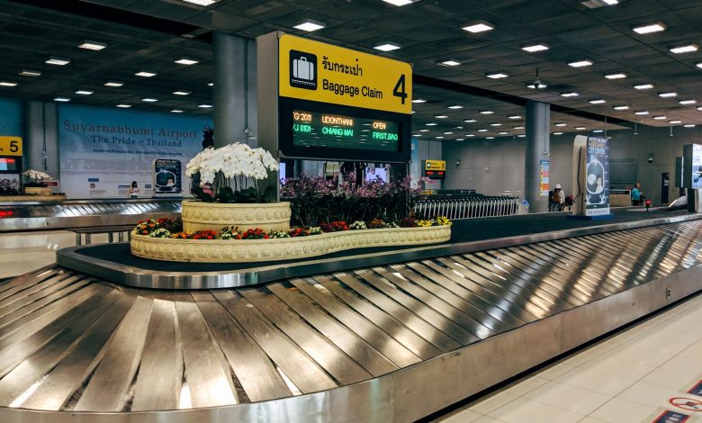 Modern baggage claim area at Suvarnabhumi Airport in Bangkok with luggage carousel and signage.