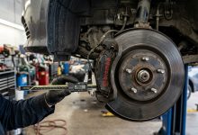 Close-up of a mechanic measuring car disc brake caliper and rotor wear