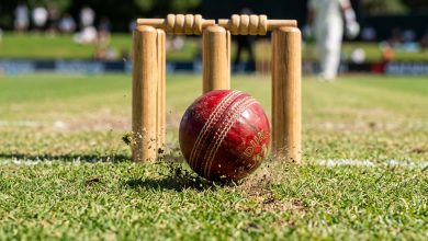 Red cricket ball pitching directly in front of the wickets